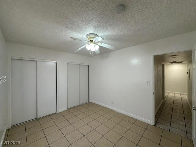 4200 Via Vaquero Ave, Las Vegas, NV 89102 - unfurnished bedroom featuring a textured ceiling, light tile patterned flooring, a ceiling fan, and two closets