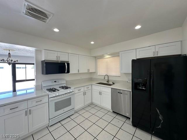 4200 Via Vaquero Ave, Las Vegas, NV 89102 - kitchen with appliances with stainless steel finishes, white cabinets, light tile patterned floors, light countertops, and a chandelier