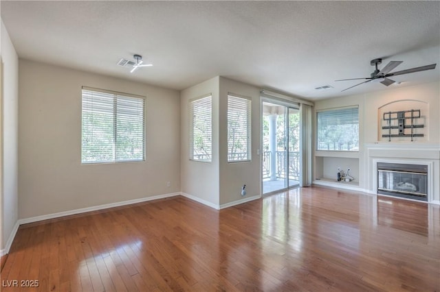 801 Dana Hills Ct Unit 101, Las Vegas, NV 89134 - unfurnished living room featuring plenty of natural light, a glass covered fireplace, hardwood / wood-style floors, and ceiling fan