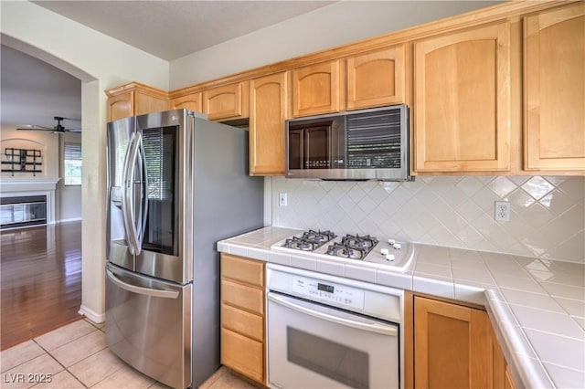 801 Dana Hills Ct Unit 101, Las Vegas, NV 89134 - kitchen with white appliances, tile countertops, decorative backsplash, ceiling fan, and light tile patterned floors