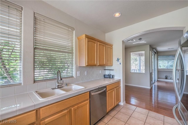 801 Dana Hills Ct Unit 101, Las Vegas, NV 89134 - kitchen featuring stainless steel appliances, tile countertops, light tile patterned flooring, arched walkways, and tasteful backsplash