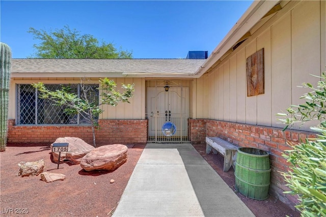 1705 Westwind Rd, Las Vegas, NV 89146 - doorway to property featuring brick siding, a shingled roof, and board and batten siding