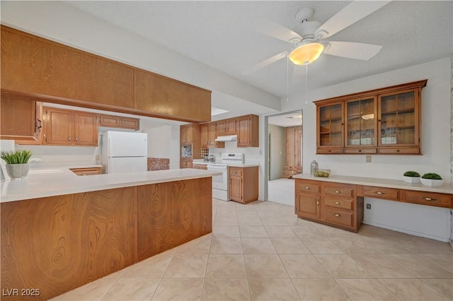1705 Westwind Rd, Las Vegas, NV 89146 - kitchen with white appliances, light countertops, brown cabinets, a peninsula, and under cabinet range hood