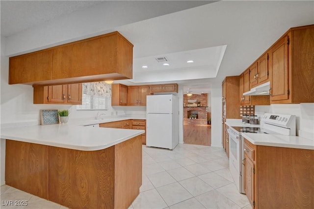1705 Westwind Rd, Las Vegas, NV 89146 - kitchen with white appliances, a peninsula, under cabinet range hood, a tray ceiling, and brown cabinetry