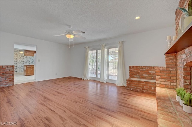 1705 Westwind Rd, Las Vegas, NV 89146 - unfurnished living room featuring a fireplace, a textured ceiling, light wood-type flooring, and a ceiling fan