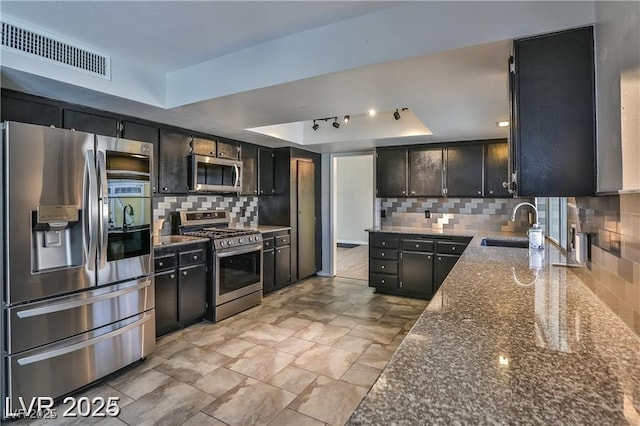 722 Barrie Ct, Henderson, NV 89002 - kitchen featuring stainless steel appliances, a raised ceiling, tasteful backsplash, and dark stone countertops
