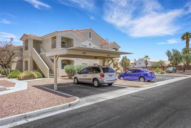 1881 W Alexander Rd Unit 2093, North Las Vegas, NV 89032 - view of front of house with stairway, covered and uncovered parking, stucco siding, and a tile roof