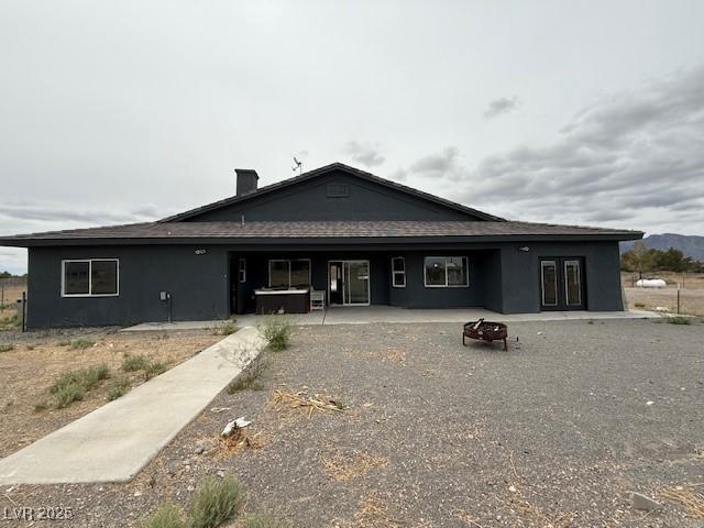 1830 Justine Ct, Pahrump, NV 89048 - back of house featuring a fire pit, a patio, a hot tub, and stucco siding