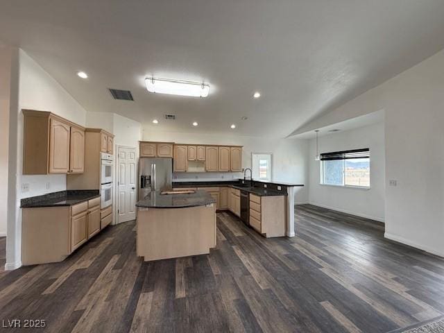 1830 Justine Ct, Pahrump, NV 89048 - kitchen with stainless steel appliances, a peninsula, dark countertops, dark wood-type flooring, and lofted ceiling