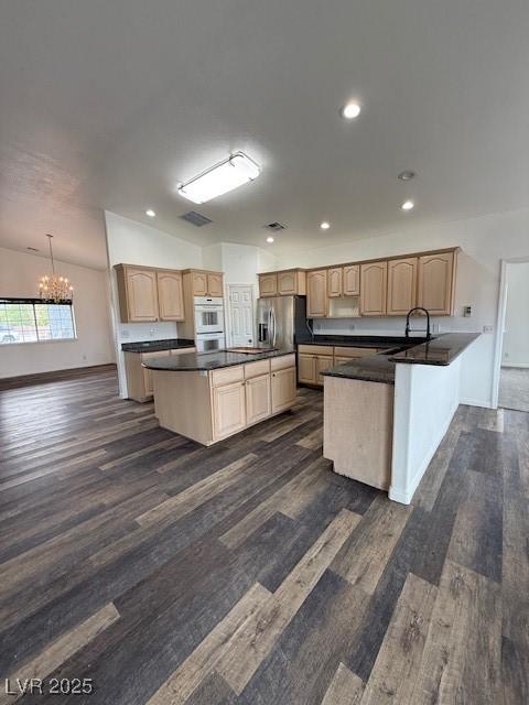 1830 Justine Ct, Pahrump, NV 89048 - kitchen with stainless steel fridge, a chandelier, light brown cabinets, dark wood-type flooring, and dark countertops