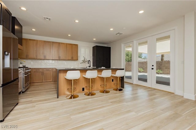 4493 Rometta Ave, Las Vegas, NV 89141 - kitchen with appliances with stainless steel finishes, french doors, a breakfast bar area, decorative backsplash, and recessed lighting