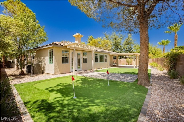 4493 Rometta Ave, Las Vegas, NV 89141 - back of property with an area to practice putting, stucco siding, a patio, a fenced backyard, and a tile roof