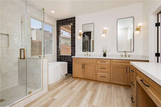 4493 Rometta Ave, Las Vegas, NV 89141 - bathroom featuring double vanity, a stall shower, a soaking tub, tile walls, and wood finished floors