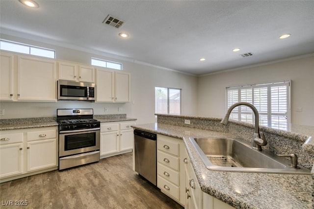 1453 Doggett Ave, Las Vegas, NV 89123 - kitchen featuring stainless steel appliances, wood finished floors, crown molding, white cabinetry, and recessed lighting