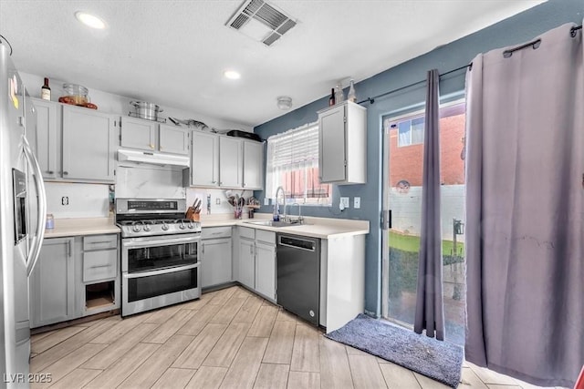 5612 Royal Castle Ln, Las Vegas, NV 89130 - kitchen with appliances with stainless steel finishes, under cabinet range hood, light countertops, light wood finished floors, and gray cabinetry