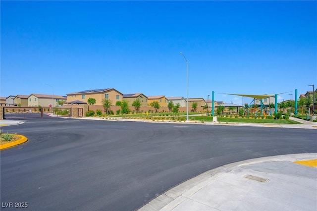 7730 Moore Creek Ln, North Las Vegas, NV 89084 - view of asphalt street with street lighting, curbs, sidewalks, a residential view, and a gate
