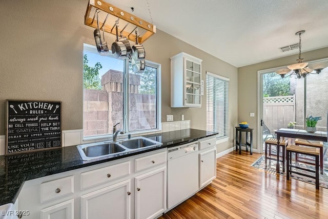 6125 Broken Slate Way, Las Vegas, NV 89139 - kitchen with dishwasher, a chandelier, white cabinetry, light wood-style flooring, and glass insert cabinets