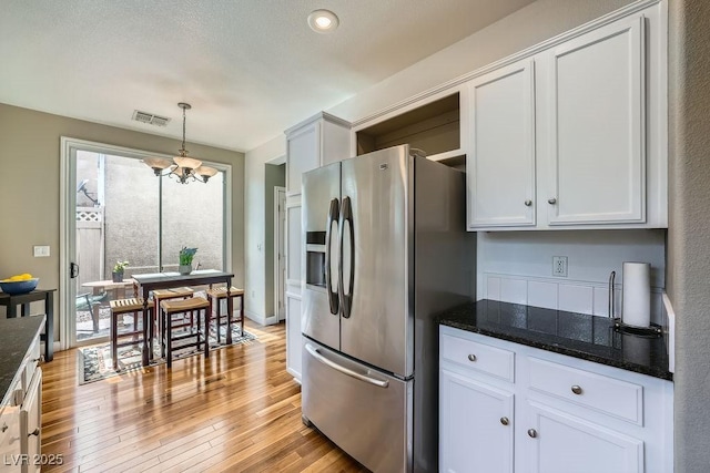 6125 Broken Slate Way, Las Vegas, NV 89139 - kitchen with stainless steel refrigerator with ice dispenser, a chandelier, light wood-type flooring, dark stone counters, and white cabinetry