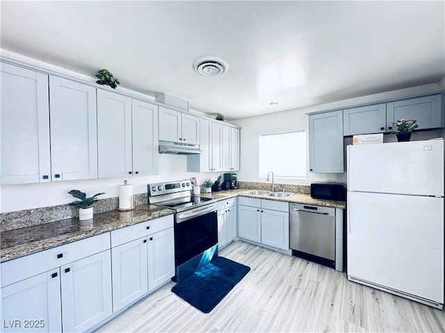 5821 Marka Dr, Las Vegas, NV 89108 - kitchen with stainless steel appliances, under cabinet range hood, dark stone counters, and light wood-type flooring