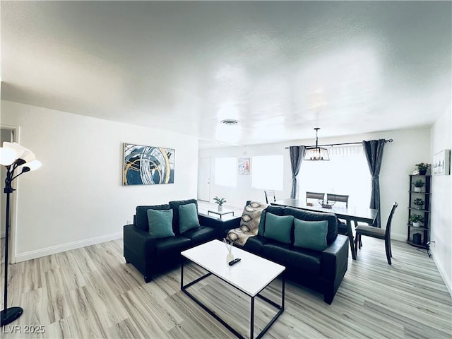 5821 Marka Dr, Las Vegas, NV 89108 - living room featuring light wood-type flooring, healthy amount of natural light, and a chandelier