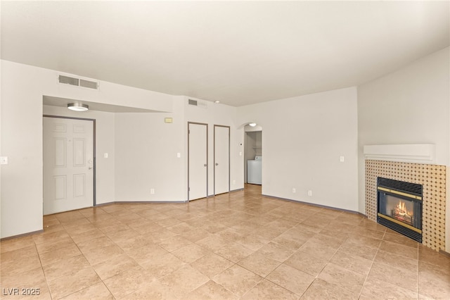 4830 Grey Wolf Ln Unit 104, Las Vegas, NV 89149 - unfurnished living room featuring washer / clothes dryer, a fireplace, and arched walkways