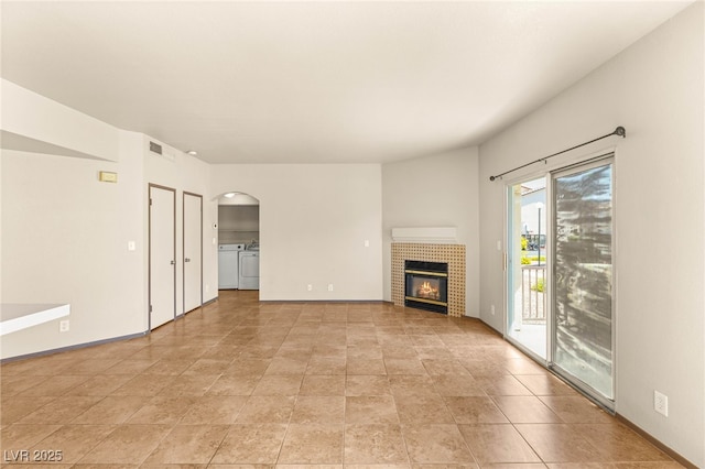 4830 Grey Wolf Ln Unit 104, Las Vegas, NV 89149 - unfurnished living room featuring independent washer and dryer, a tiled fireplace, and arched walkways
