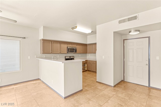 4830 Grey Wolf Ln Unit 104, Las Vegas, NV 89149 - kitchen featuring appliances with stainless steel finishes, light countertops, a peninsula, and light tile patterned floors