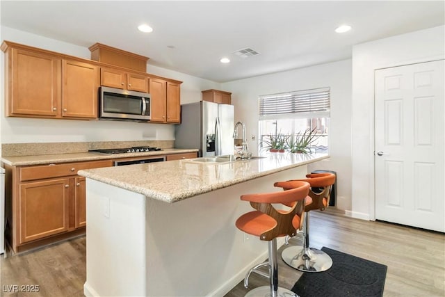 10013 Sable Point St, Las Vegas, NV 89178 - kitchen featuring stainless steel appliances, light wood finished floors, a kitchen breakfast bar, a kitchen island with sink, and recessed lighting