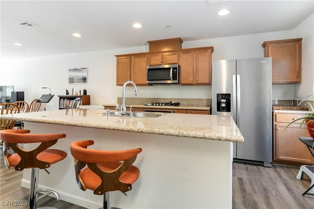 10013 Sable Point St, Las Vegas, NV 89178 - kitchen with appliances with stainless steel finishes, light wood-type flooring, a breakfast bar, a kitchen island with sink, and light stone countertops