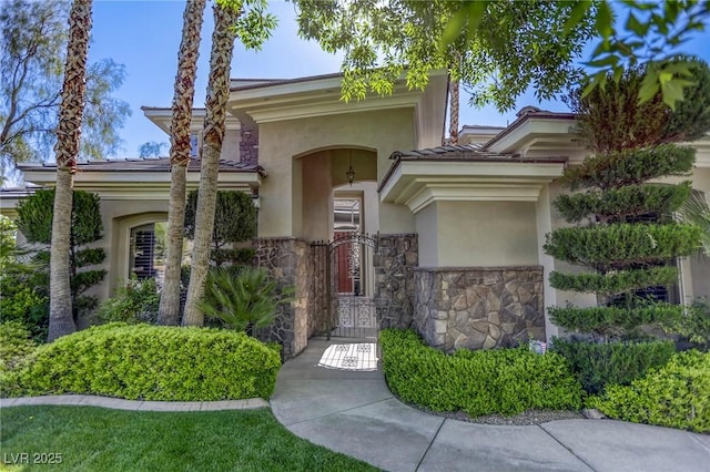 2008 Winter Wind St, Las Vegas, NV 89134 - view of exterior entry with stucco siding, stone siding, a tile roof, and a gate
