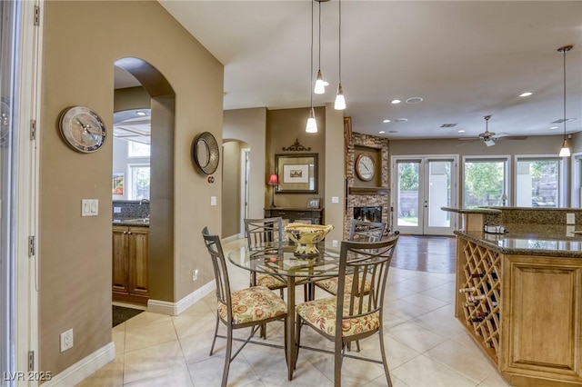 2008 Winter Wind St, Las Vegas, NV 89134 - dining space featuring arched walkways, ceiling fan, light tile patterned flooring, a stone fireplace, and recessed lighting
