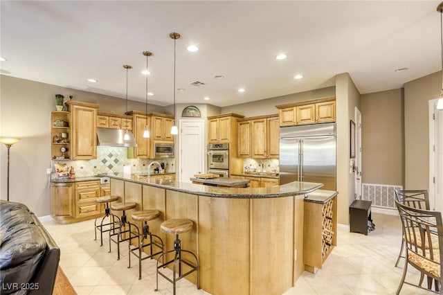 2008 Winter Wind St, Las Vegas, NV 89134 - kitchen with under cabinet range hood, built in appliances, a large island with sink, light tile patterned floors, and a kitchen breakfast bar