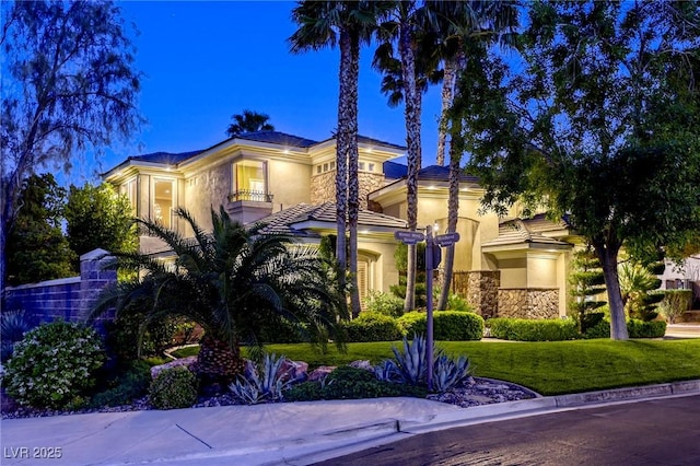 2008 Winter Wind St, Las Vegas, NV 89134 - mediterranean / spanish home featuring stone siding, stucco siding, a balcony, and a front lawn