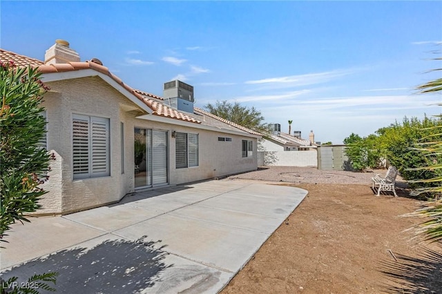 6209 Lenaking Ave, Las Vegas, NV 89122 - rear view of house featuring a chimney, a patio, a tile roof, a storage shed, and stucco siding