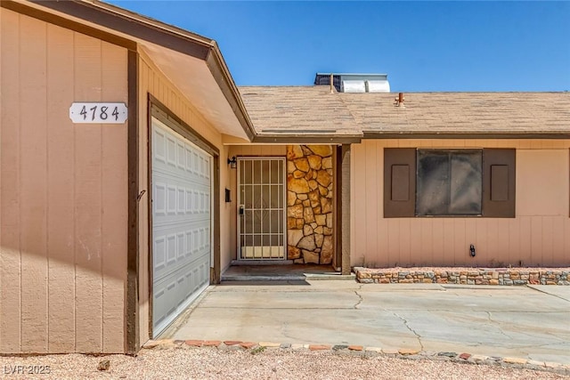 4784 El Escorial Dr, Las Vegas, NV 89121 - doorway to property featuring a shingled roof, a garage, and stone siding