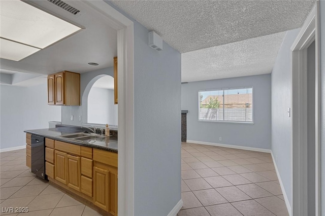 4784 El Escorial Dr, Las Vegas, NV 89121 - kitchen featuring black dishwasher, light tile patterned floors, dark countertops, arched walkways, and a textured ceiling