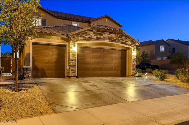 7311 Spring Flower Ave, Las Vegas, NV 89117 - mediterranean / spanish-style home with stone siding, concrete driveway, a tiled roof, stucco siding, and a garage