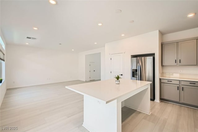5804 Gossamer Stone Ct, Las Vegas, NV 89141 - kitchen with gray cabinetry, stainless steel refrigerator with ice dispenser, light countertops, light wood-style flooring, and a kitchen island