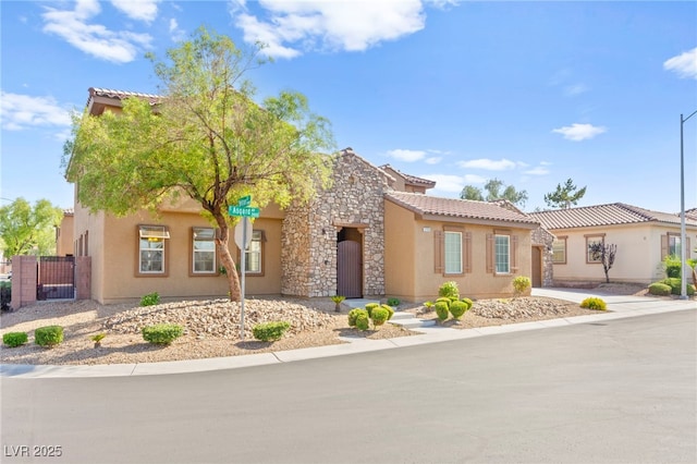 2755 Asgard Ave, Las Vegas, NV 89121 - view of front of house with stucco siding, a tiled roof, a gate, and stone siding