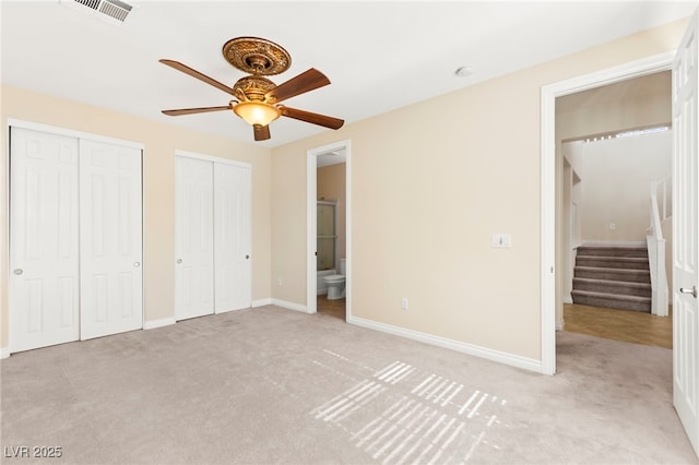 2755 Asgard Ave, Las Vegas, NV 89121 - unfurnished bedroom with light colored carpet, two closets, ensuite bathroom, and ceiling fan