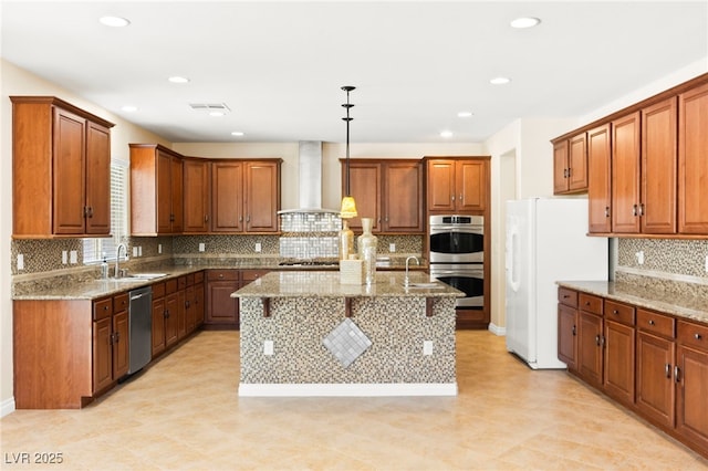 2755 Asgard Ave, Las Vegas, NV 89121 - kitchen with wall chimney exhaust hood, appliances with stainless steel finishes, light stone counters, brown cabinetry, and recessed lighting
