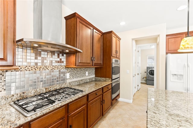 2755 Asgard Ave, Las Vegas, NV 89121 - kitchen with appliances with stainless steel finishes, wall chimney range hood, washer / clothes dryer, decorative backsplash, and light stone countertops