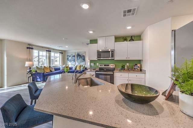 7965 Aurora Sky St Unit 621, North Las Vegas, NV 89084 - kitchen with stainless steel appliances, open floor plan, white cabinetry, light stone countertops, and recessed lighting
