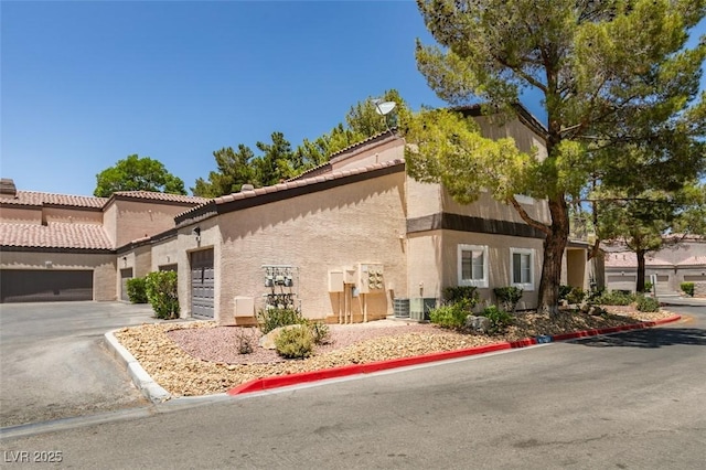5250 S Rainbow Blvd Unit 2101, Las Vegas, NV 89118 - view of side of property with stucco siding, a tile roof, an attached garage, and asphalt driveway