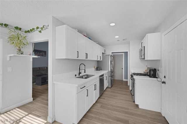 59 N Christy Ln, Las Vegas, NV 89110 - kitchen with appliances with stainless steel finishes, light countertops, white cabinetry, light wood-style floors, and recessed lighting