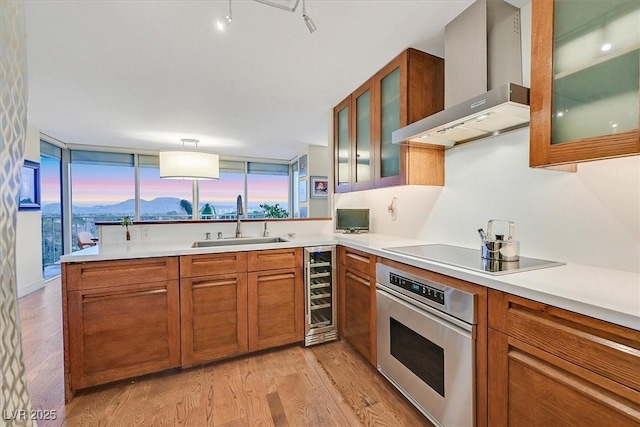 3111 Bel Air Dr Unit 7D, Las Vegas, NV 89109 - kitchen with wall chimney range hood, stainless steel oven, wine cooler, and light wood finished floors