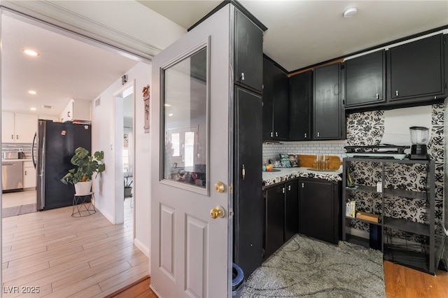 2990 Carnelian St, Las Vegas, NV 89121 - kitchen featuring dark cabinets, appliances with stainless steel finishes, decorative backsplash, and light wood-style flooring