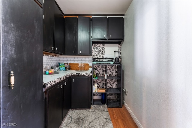 2990 Carnelian St, Las Vegas, NV 89121 - kitchen featuring dark cabinets, light wood finished floors, decorative backsplash, light countertops, and freestanding refrigerator