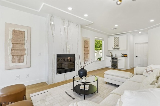 2469 Sun Reef Rd, Las Vegas, NV 89128 - living room with wine cooler, bar with sink, light wood finished floors, recessed lighting, and a fireplace