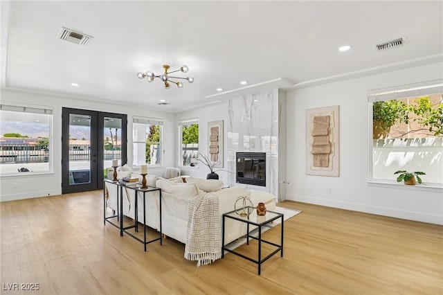 2469 Sun Reef Rd, Las Vegas, NV 89128 - living room featuring healthy amount of natural light, light wood-style floors, french doors, recessed lighting, and a premium fireplace